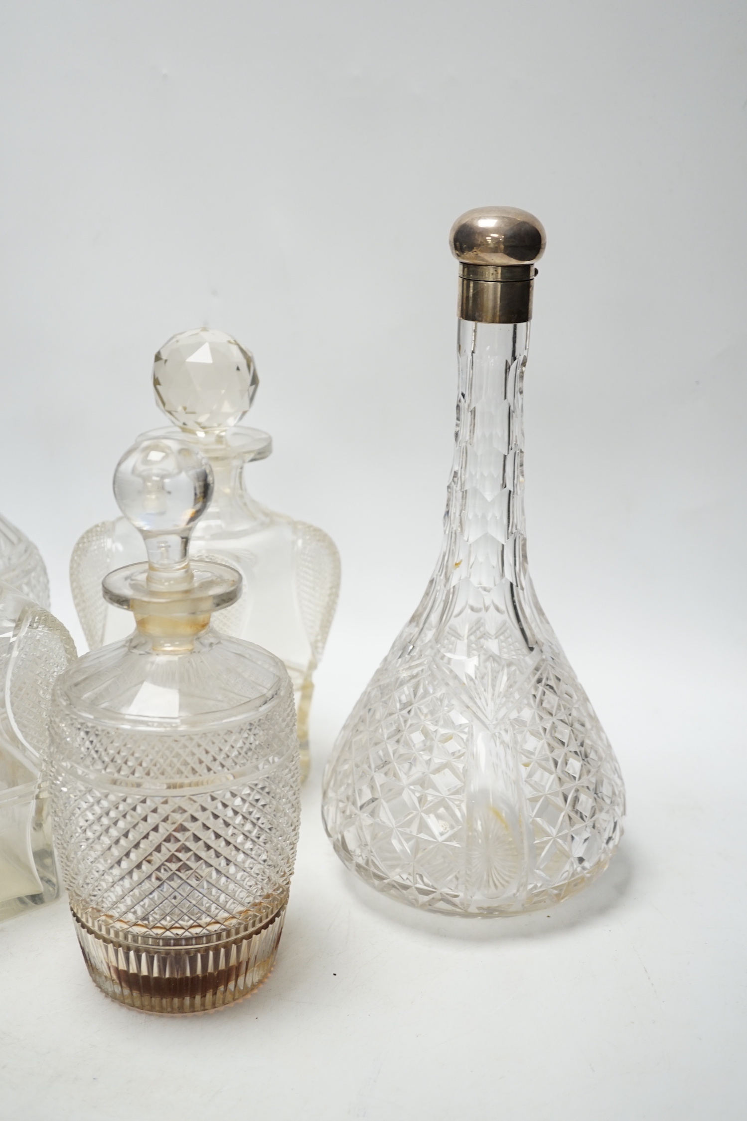 Two silver mounted glass decanters, a pair of waisted cut glass decanters and one other, tallest 29cm high (5)